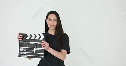 Young female assistant bangs clapperboard standing on white