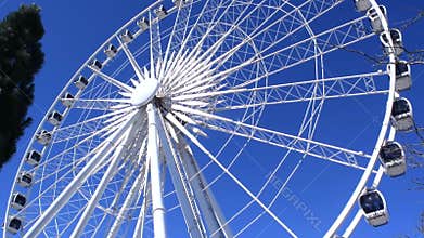 White giant ferris wheel close-up on a sunny day against a blue sky.
