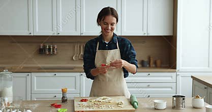 Happy young baker woman in chief apron baking in kitchen