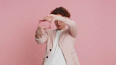 Man photographer gesturing picture frame with hands, looks through fingers focusing cropping image