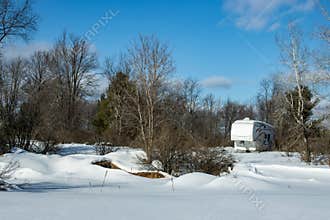A fifth-wheel camper trailer parked in a snowy field with trees in winter