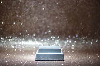 A shiny silver bar sits on a surface covered in shimmering sparkles in a bright setting captured in the afternoon light