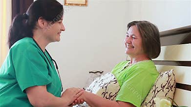 Senior woman talking and laughing with her home caregiver nurse