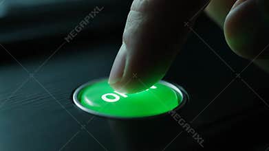 Finger Pressing a Green Open Button on a Black Surface in the Evening
