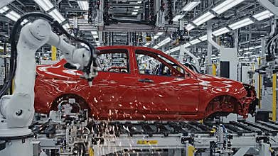 Automated Robotic Arms Assemble Red Car Chassis on Modern Assembly Line Under Bright Industrial Factory Lighting