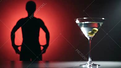 Elegant Martini with Olives and Shadow of Person in Red and Black Background for Nightlife Advertising and Cocktail Promotion with