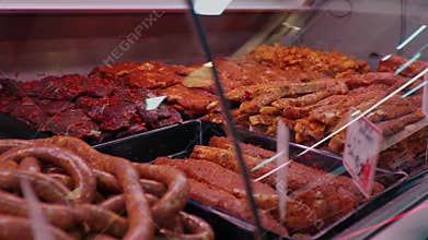 Fresh raw and marinated meat with tags on the showcase in the butchers store.