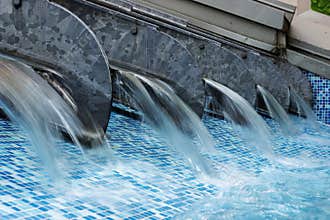 Modern water cascade in blue tiled pool