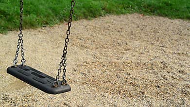 Empty swing seat swaying at playground in the park.