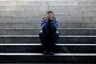 Young homeless man lost job sitting in depression on ground street concrete stairs