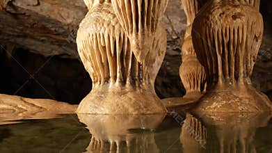 Illustrating the slow, continuous process of mineral deposition, with clear water droplets forming and falling from stalactite