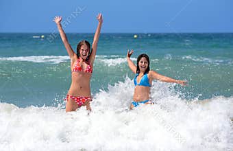 Two attractive young girl friends playing in the sea on vacation