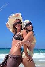 Two young girls or friends playing on a sunny beach on vaca