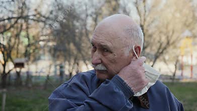 Elderly man taking off his face mask