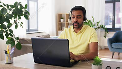 Indian man with headset and laptop working at home