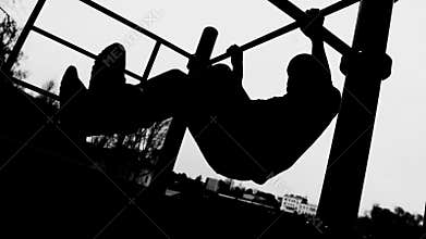 Silhouette of an athlete on a horizontal bar. Side view