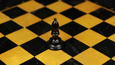 Chess black bishop figure in a middle of playing board close-up. Rotation.