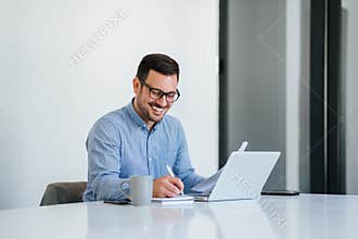 Portrait of a cheerful man having video call on laptop computer cheerful businessman using laptop in bright office space young.