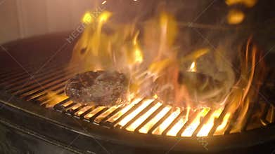 Juicy beef burgers grilled on the barbecue with fire from the charcoal