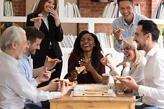 Cheerful multiracial office business people laugh share takeaway pizza together