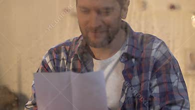Man reading letter behind wet window, sun rays shining, belief in better, hope