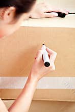 Delighted woman writing on a box