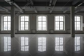 Empty large room in old factory building with row of big windows, columns and pipes under the beton ceiling