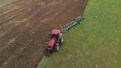 Farmer on an energy saturated tractor produces plowing with a turnover of the soil layer with a modern plow in cloudy