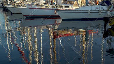 Masts of ships are reflected in the water. Modern ships are in the bay. Panorama from bottom to top