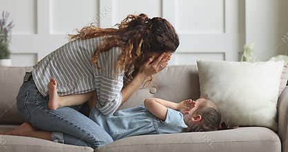 Playful mother and cute child daughter playing peek a boo