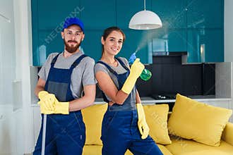 Couple of professional cleaners stay together in the contemporary cuisine with detergents. House cleaning services