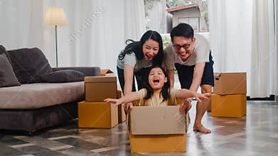 Happy Asian young family having fun laughing moving into new home. Japanese parents mother and father smiling helping excited