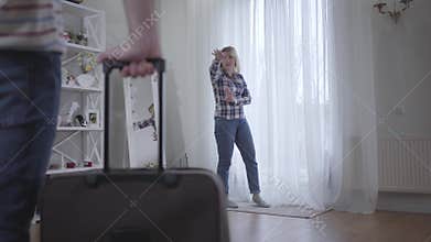 Portrait of angry Caucasian woman kicking out husband. Nervous stressed wife yelling and gesturing as unrecognizable man