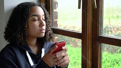 Sad or depressed beautiful mixed race African American girl teenager using her cell phone for social media