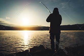 Silhouette fisherman with fishing rod at sunrise sunlight, outline man enjoy hobby sport on evening lake, person catch fish