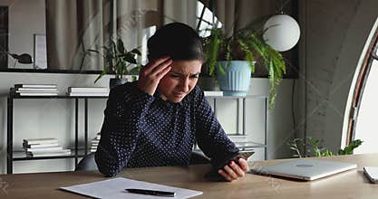 Confused unhappy indian businesswoman frustrated about phone problem in office