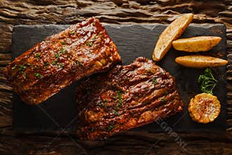 Food background of BBQ barbeque pork ribs served with potato fried and baked corn, selective focus