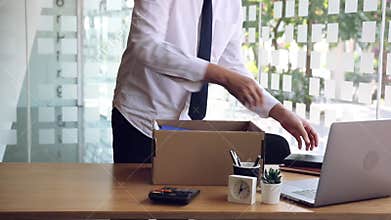 Young male employee standing near work table putting his stuff from in carton box belongings after being dismissed resignation