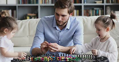 Happy loving young dad playing with cute daughters at home