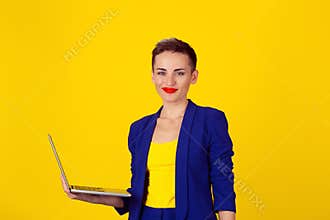 Beautiful happy woman  smiling kindly standing with laptop over yellow background