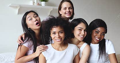 Happy smiling millennial female friends enjoying pajama party.