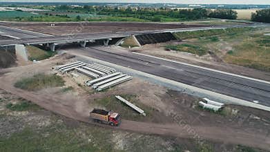 Flying a copter over a truck driving on the road. Construction of a traffic intersection. Column of dust from a passing
