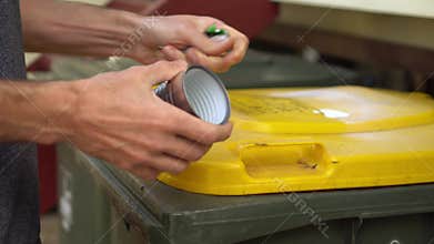 Person removes label from tin can, puts can in recycle bin and label in trash bin