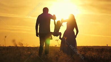 Mom, dad and baby play outdoors. healthy little daughter jumps and flies in arms of mother and father in field at sunset