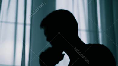 Anonymous blurred silhouette of a man talking on a cell phone, a criminal is extorting money