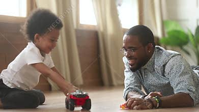 Happy african cute little son playing toy cars with dad
