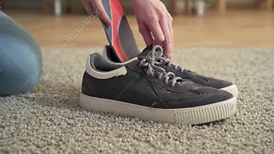 Woman inserts orthopedic insoles into shoes