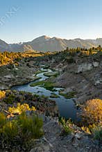 Winding bubbling river at Hot Creek Geological Site in Mammoth Lakes California, with the Eastern Sierra Nevada mountains in