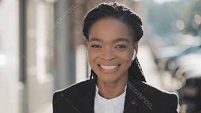 Portrait of stylish afro business woman standing on the old street background. She looking at the camera and smiling
