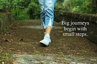 Inspirational quote- Big journeys begin with small steps. With feet of young woman walking surrounding with fresh green nature